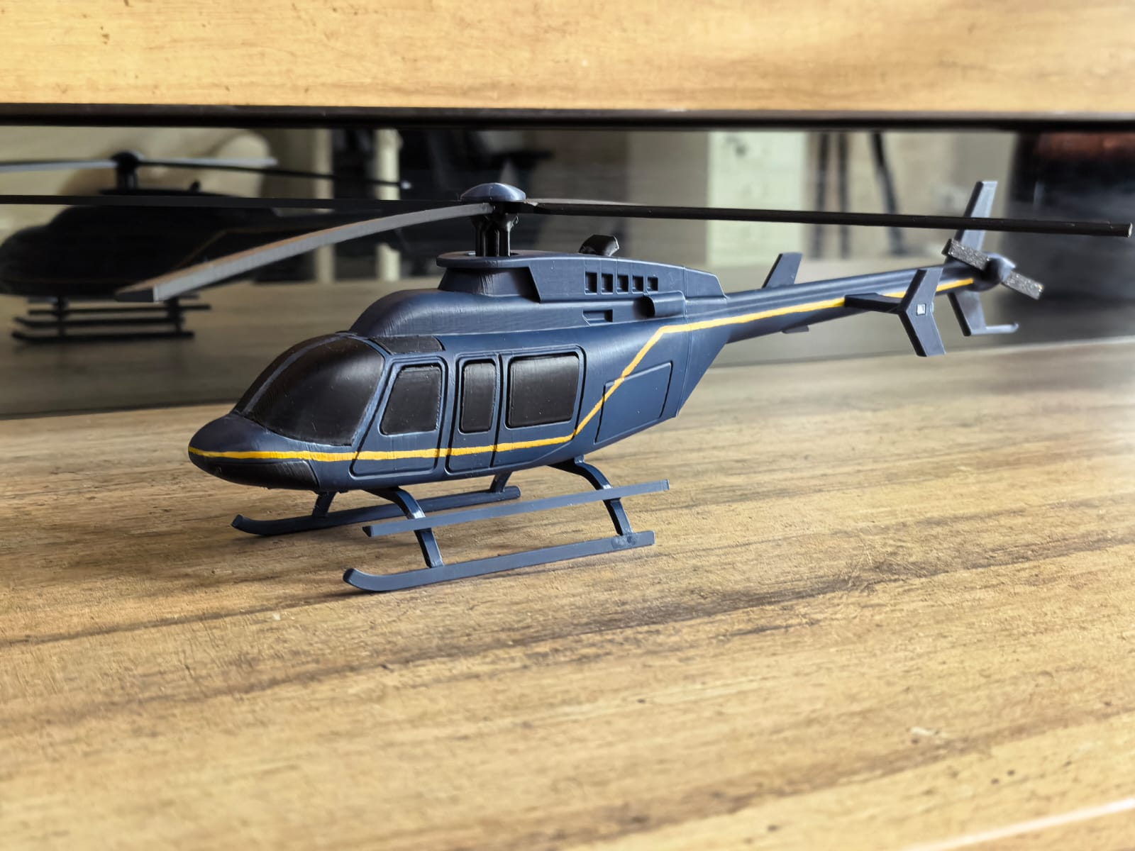 Real navy and gold helicopter prototype on a wooden table, photographed from the side